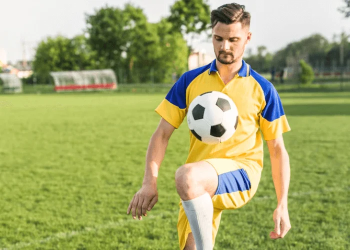 Senior guy posing with a football to showcase athletic skills, creating a personalized and dynamic senior graduation portrait.