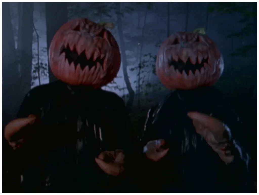 Two pumpkin heads telling ghost stories around a bonfire during a spooky Halloween photoshoot