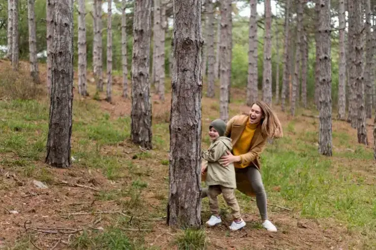 Mother and daughter peeking around a tree photography