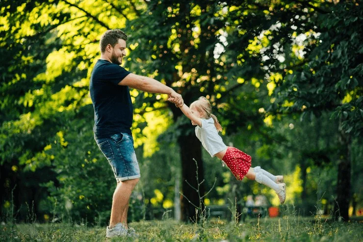 father and daughter swinging in the park